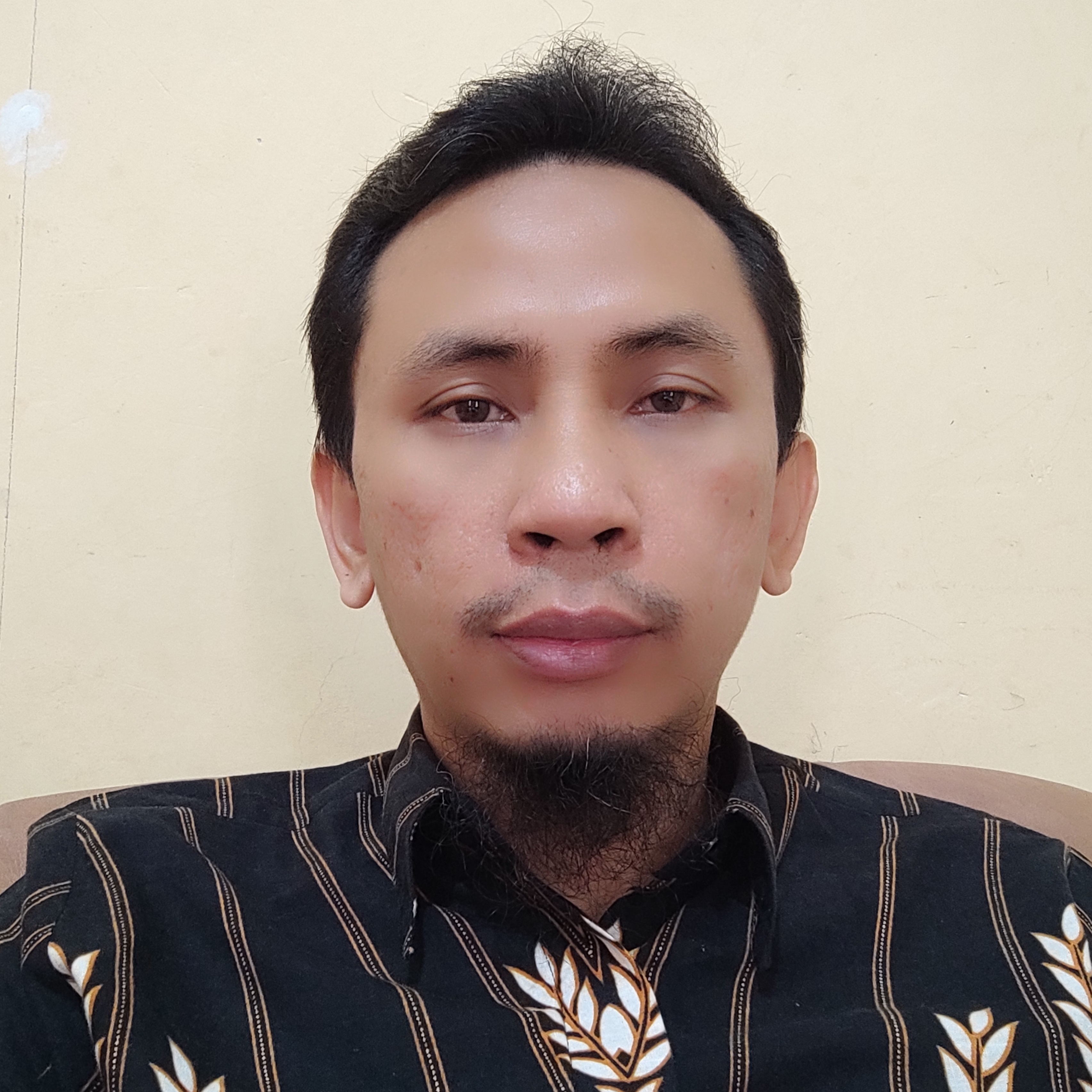 Potret profesional Wandi Syahindra dengan background biru muda, mengenakan kemeja formal warna putih, tersenyum ramah dengan ekspresi percaya diri, cahaya profesional studio fotografi